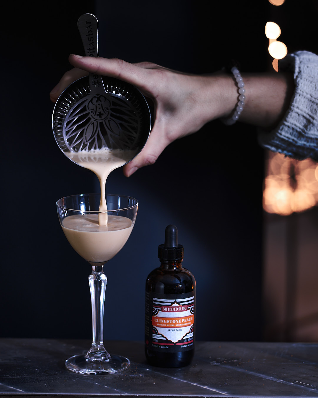 Bitter Alexander Cocktail being poured into a glass with Clingstone Peach bitters beside